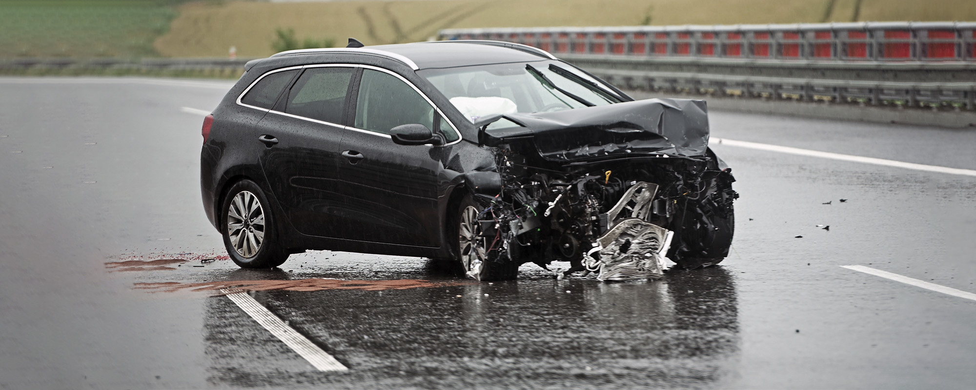badly damaged front of a car on a highway right after head on barrier collision in heavy rain. rainy weather dangerous d