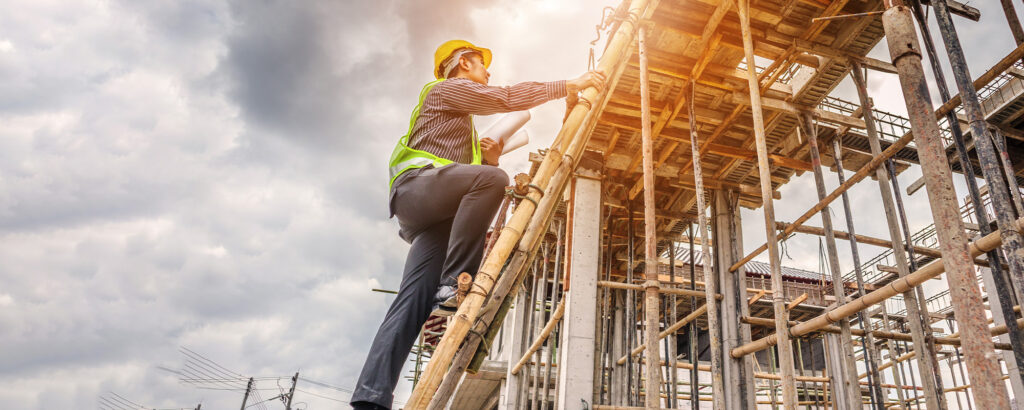Construction worker climbing scaffolding at building site with fall risk exposure