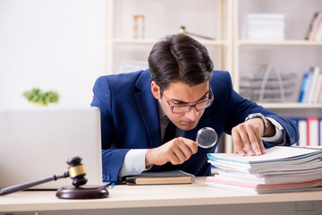 man looking through stack of papers with magnifying glass