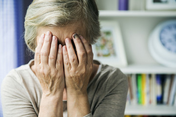 older woman upset with her head in her hands